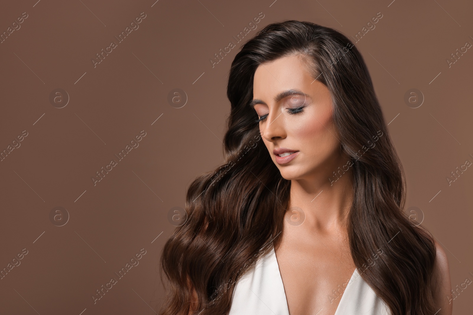 Photo of Hair styling. Beautiful woman with wavy long hair on brown background, space for text