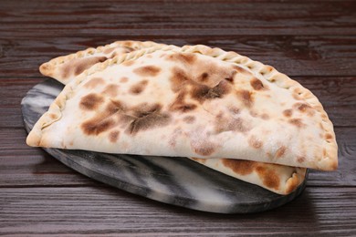 Photo of Delicious calzones on wooden table, closeup view
