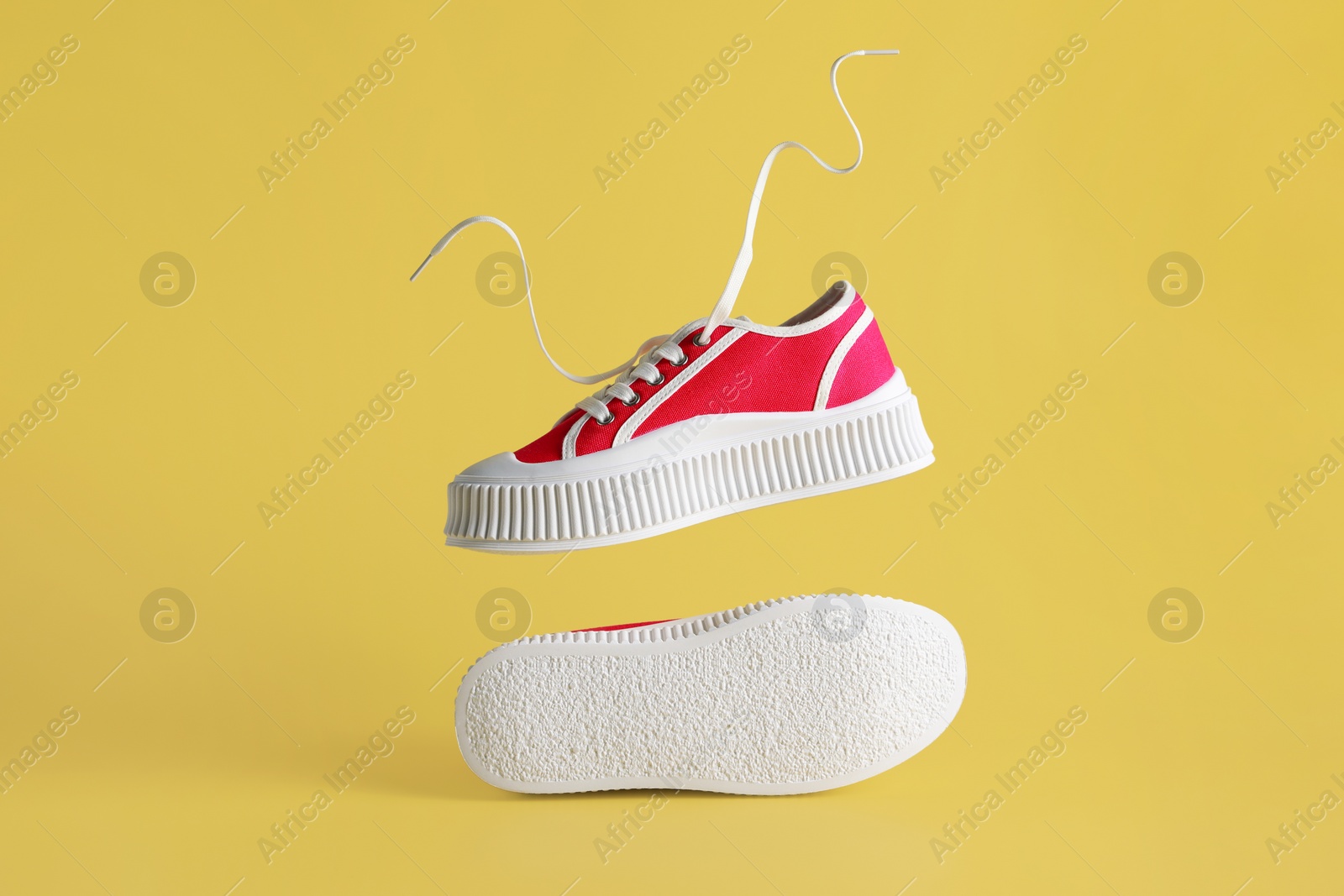 Photo of Pair of red classic old school sneakers on yellow background