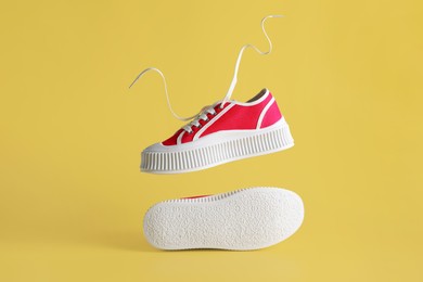 Photo of Pair of red classic old school sneakers on yellow background