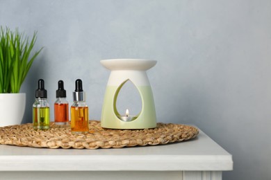Photo of Aroma lamp and essential oils on white table