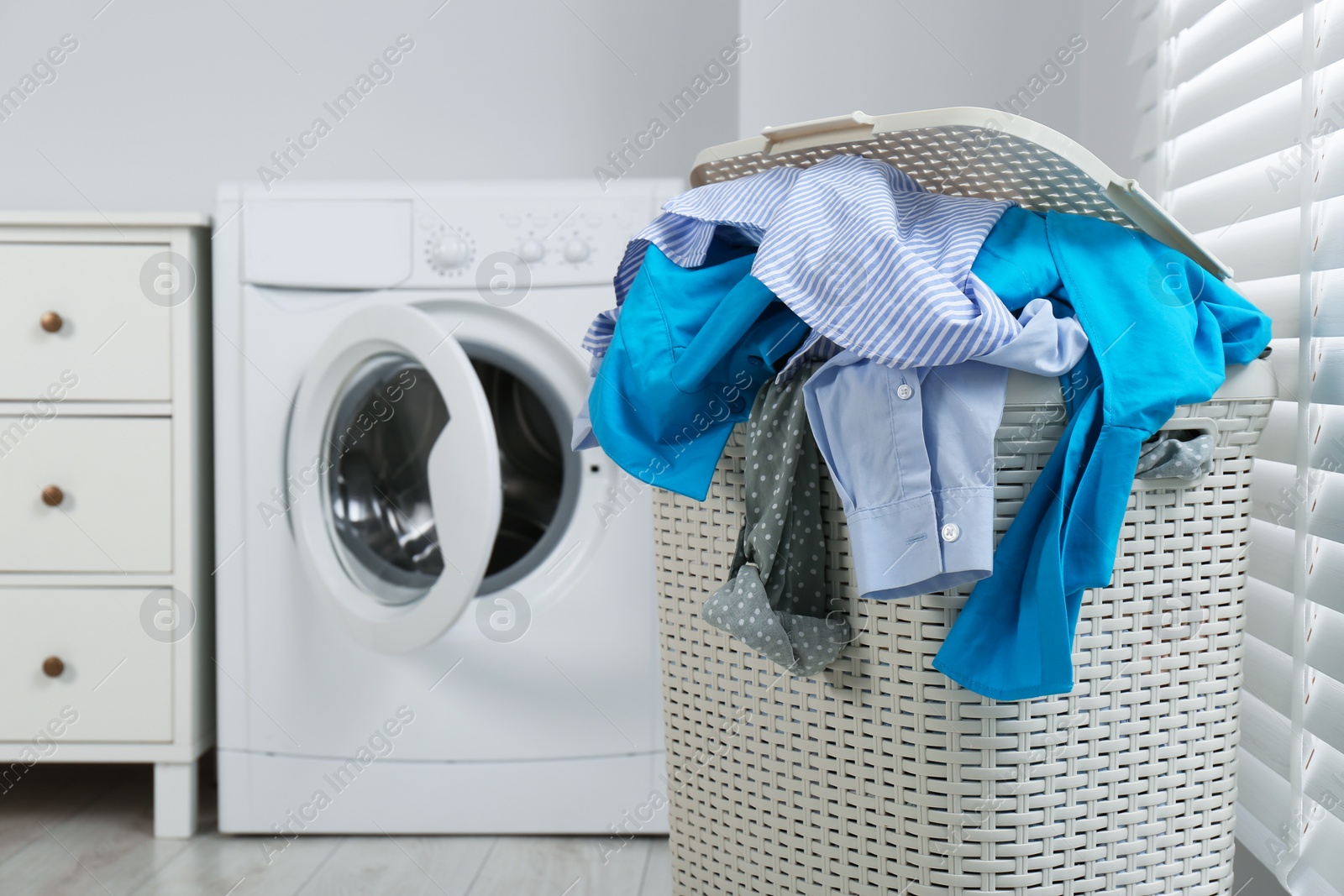 Photo of Plastic laundry basket overfilled with clothes in bathroom. space for text