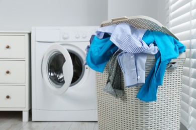 Photo of Plastic laundry basket overfilled with clothes in bathroom. space for text