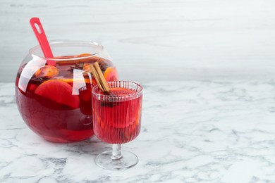 Photo of Glass and bowl of delicious aromatic punch drink on white marble table. Space for text