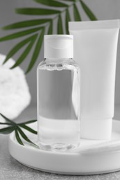 Photo of Micellar water and cream on grey table, closeup