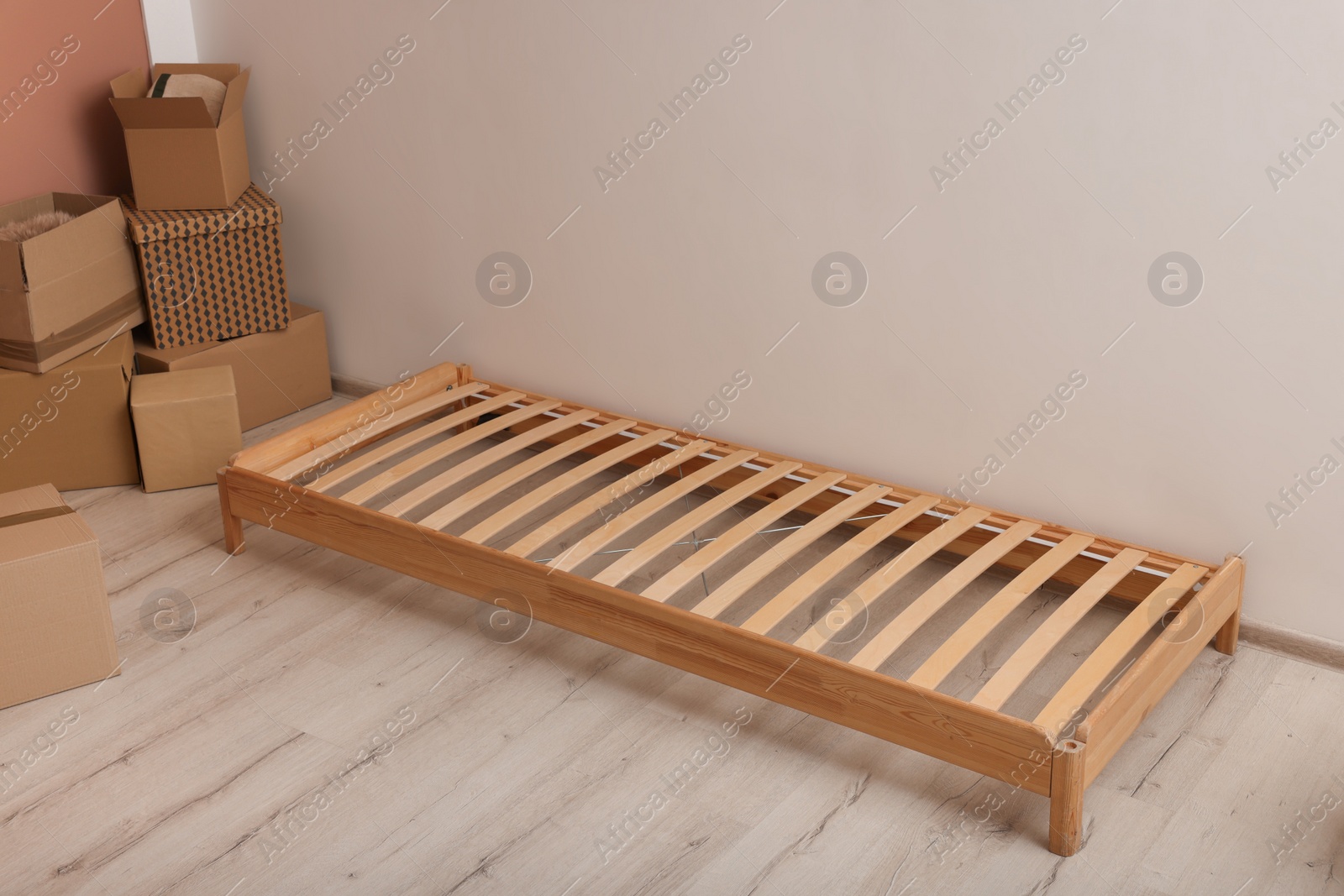 Photo of Wooden bed frame and cardboard boxes on floor in room