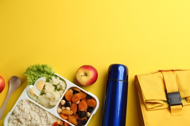 Flat lay composition with thermos and food on yellow background. Space for text