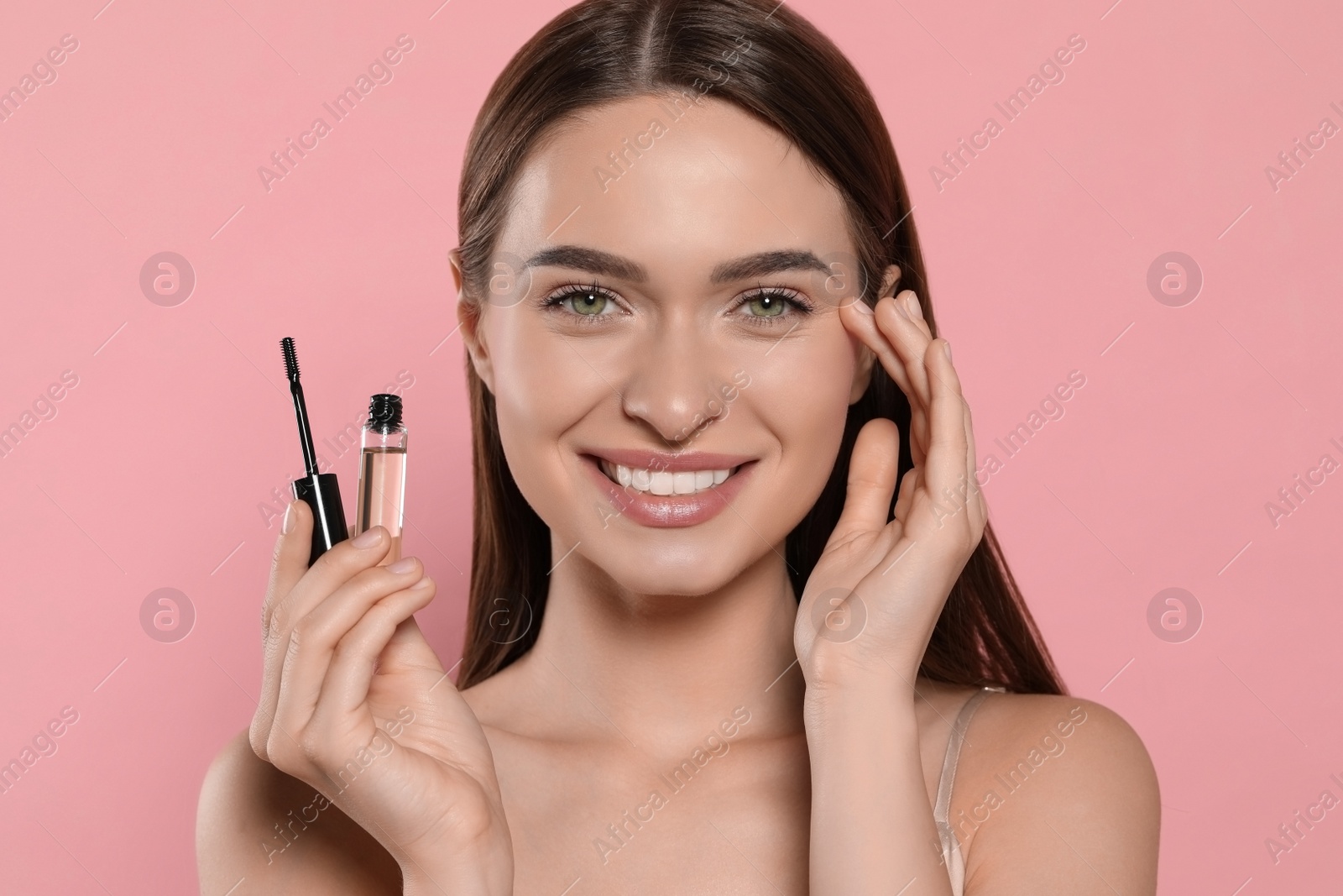 Photo of Young woman with eyelash oil on pink background