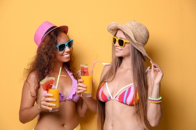 Photo of Beautiful young women in beachwear with cocktails on color background