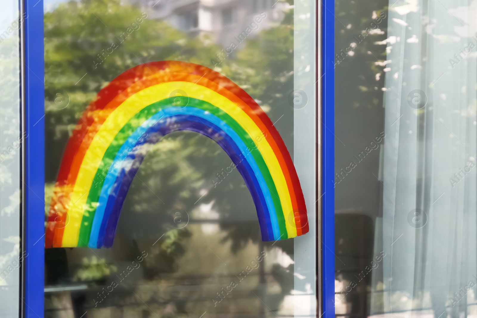 Photo of Painting of rainbow on window, view from outdoors. Stay at home concept