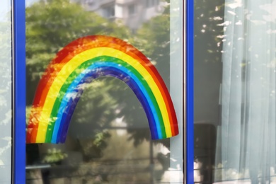 Painting of rainbow on window, view from outdoors. Stay at home concept
