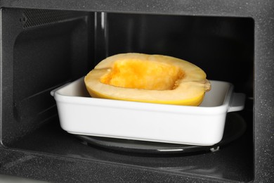 Photo of Baking dish with half of fresh spaghetti squash in microwave oven