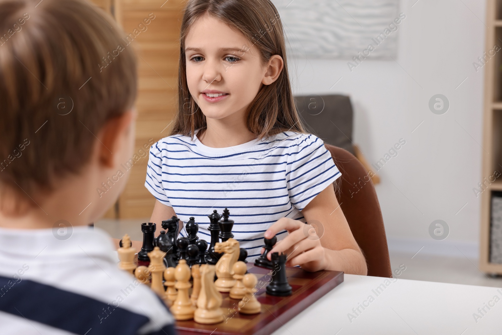 Photo of Cute children playing chess at table in room