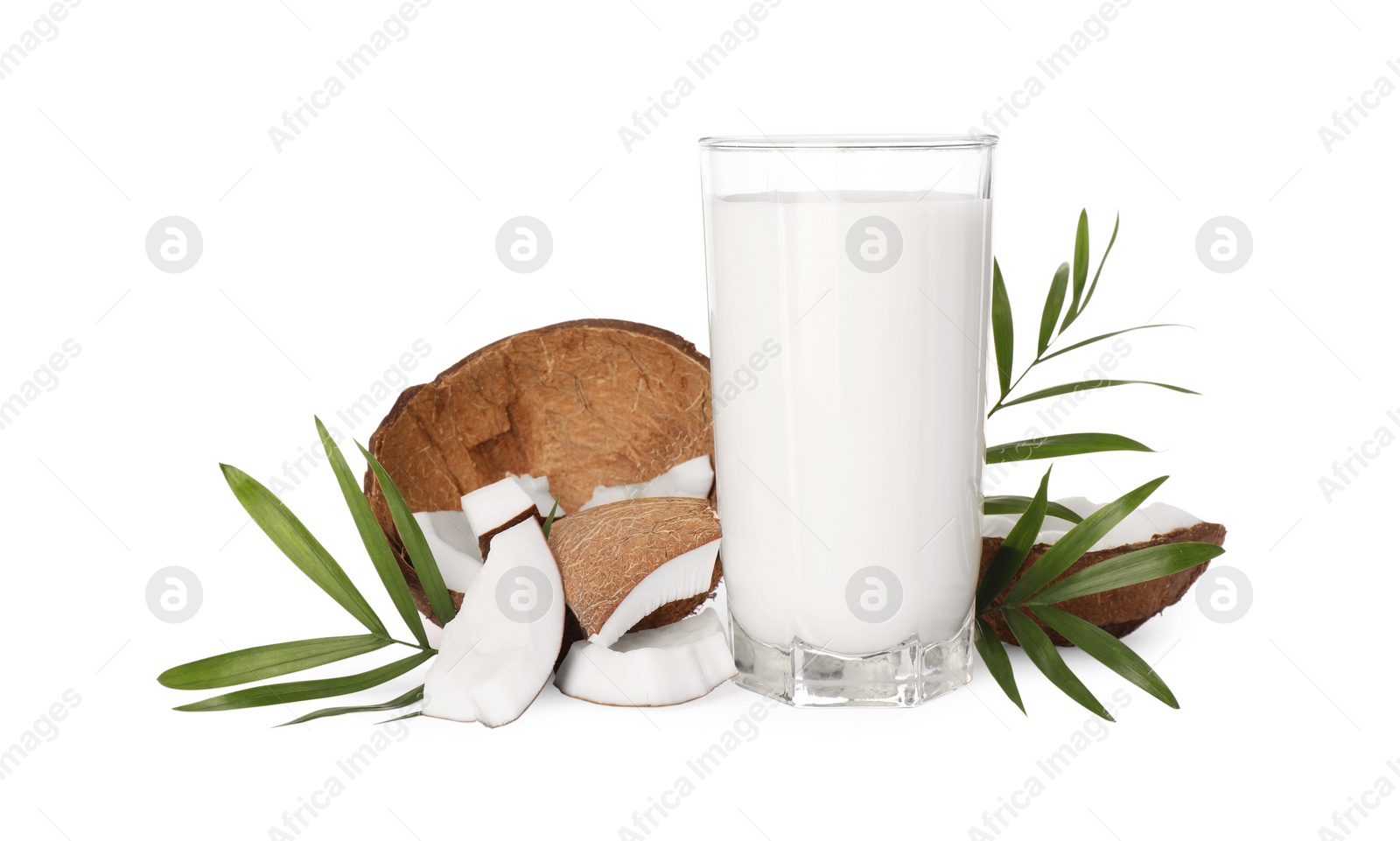 Photo of Glass of delicious vegan milk, coconut pieces and green leaves on white background