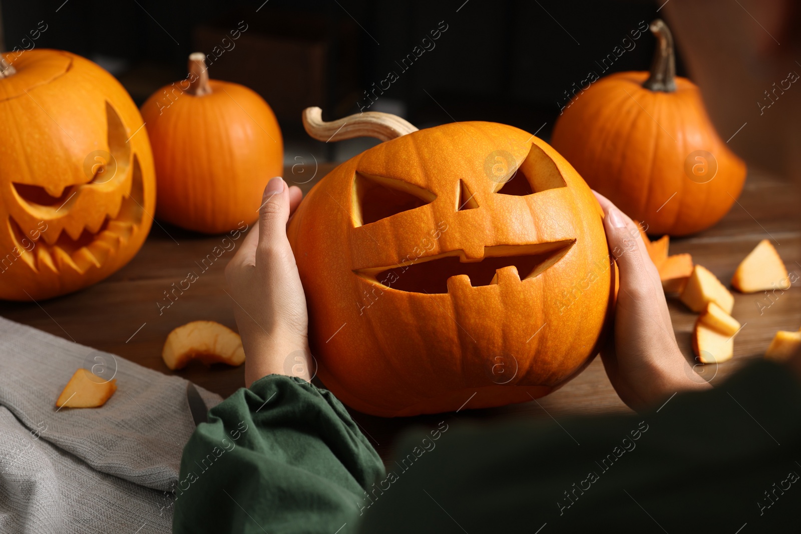 Photo of Woman holding carved pumpkin for Halloween at wooden table, closeup