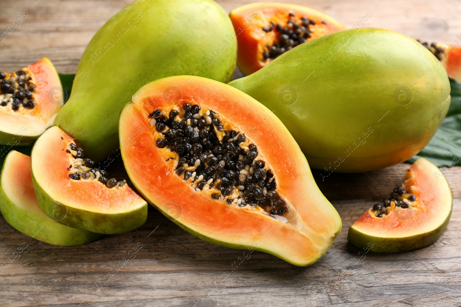 Photo of Fresh ripe papaya fruits on wooden table, closeup