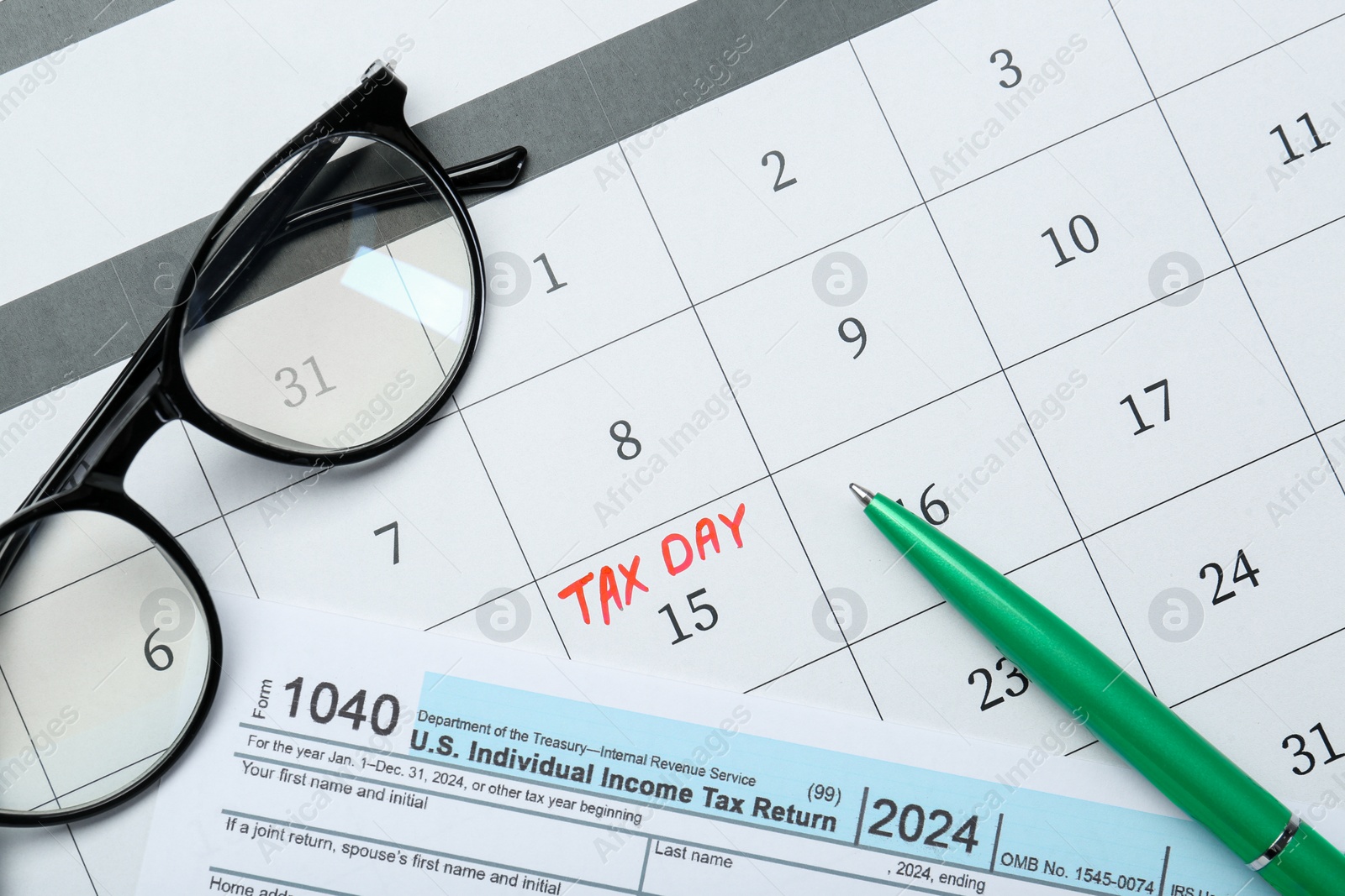 Photo of Tax day. Calendar with date reminder, document, pen and glasses on table, flat lay