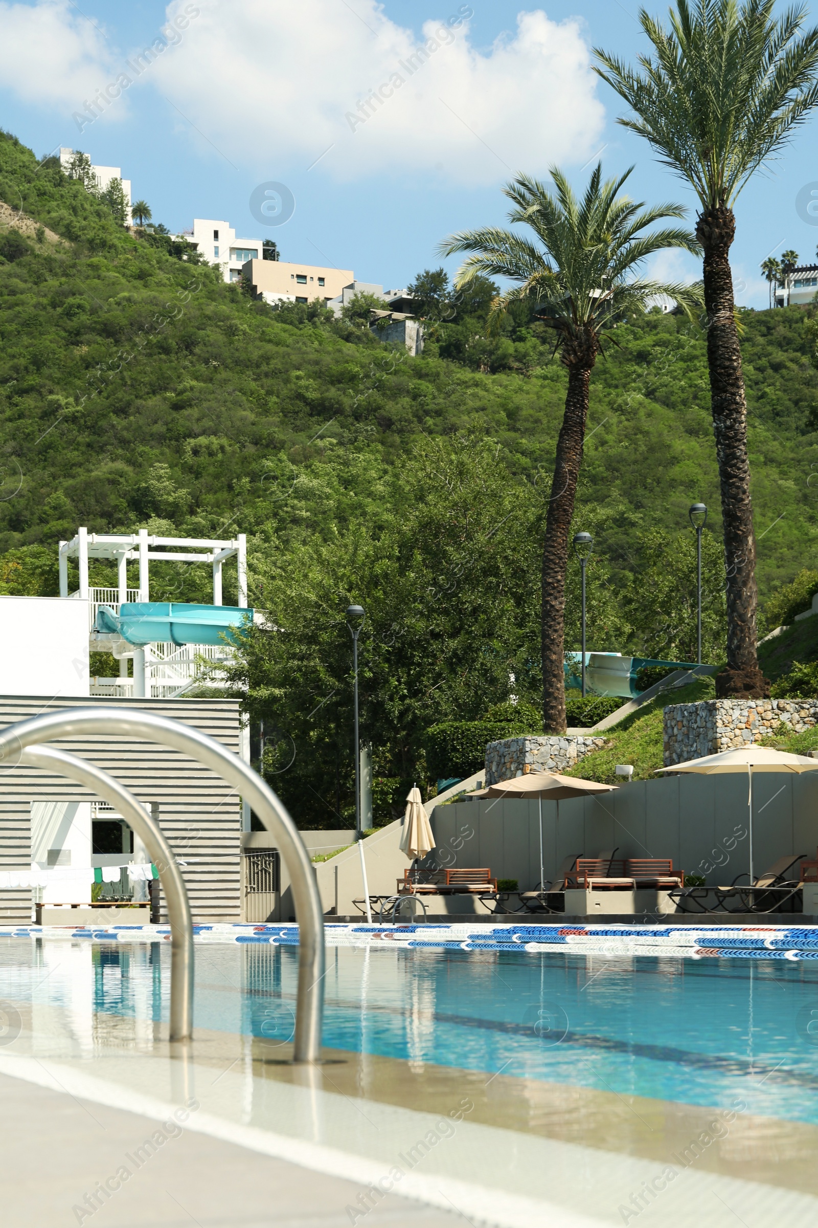 Photo of Outdoor swimming pool and tropical plants at luxury resort on sunny day