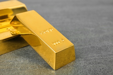 Photo of Shiny gold bars on table, closeup. Space for text