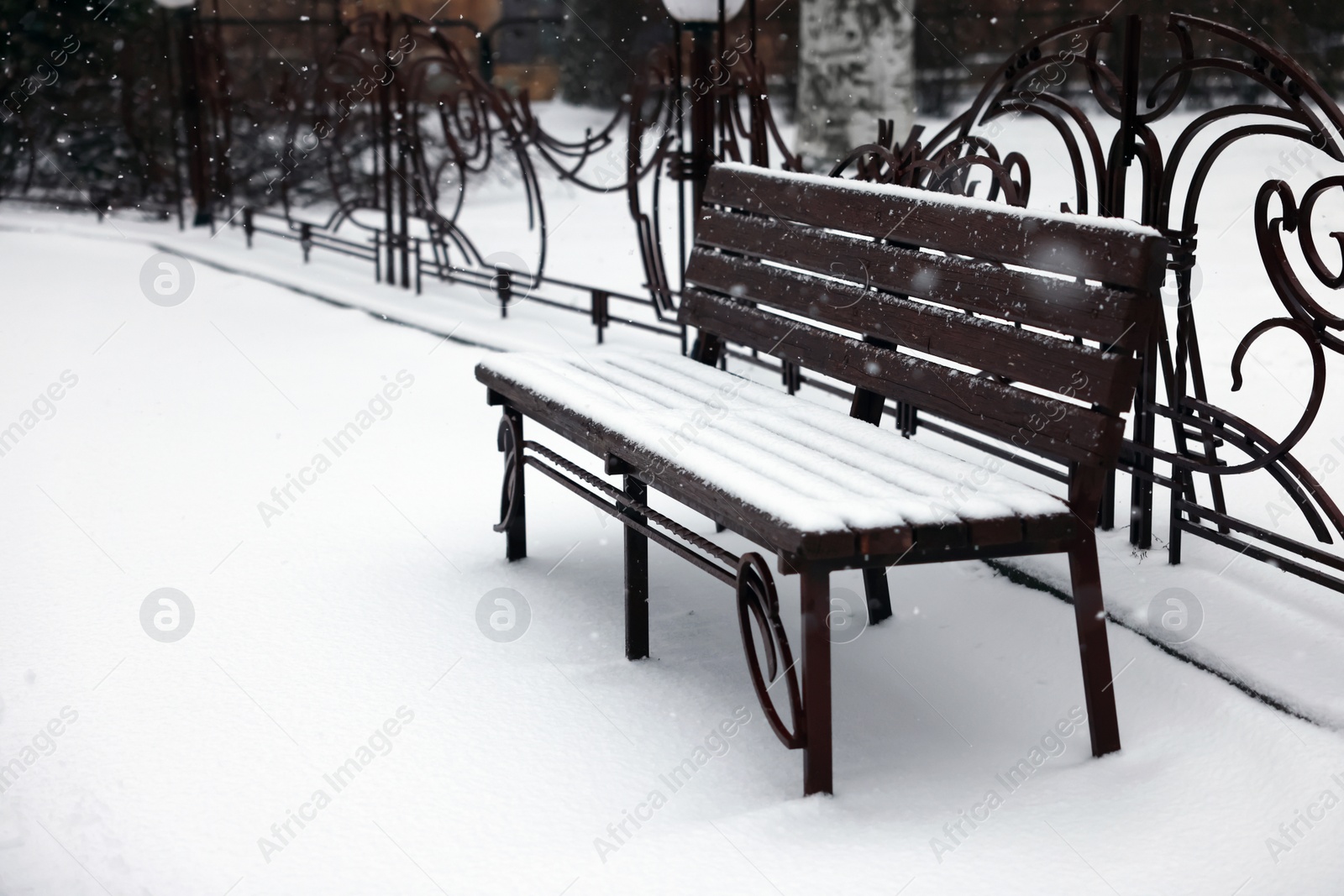 Photo of Bench covered with snow in city park