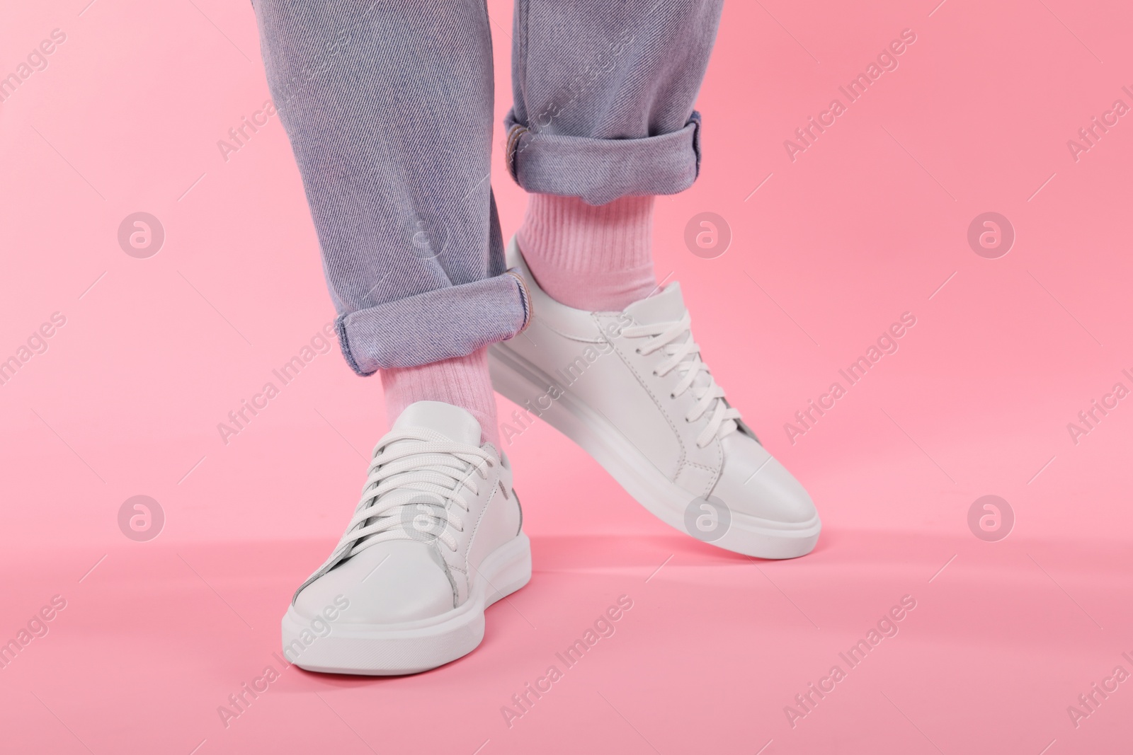 Photo of Woman wearing stylish white sneakers on pink background, closeup