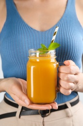 Photo of Woman with mason jar of natural peach juice, closeup