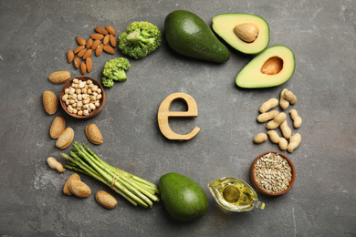 Wooden letter and different products rich in vitamin E on grey background, flat lay