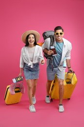 Photo of Couple of tourists with tickets, passports and suitcases on pink background