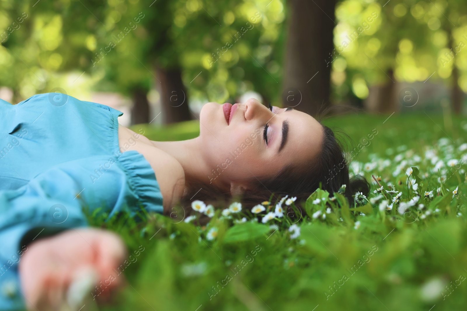 Photo of Beautiful woman lying on green grass in park. Spring sunny day