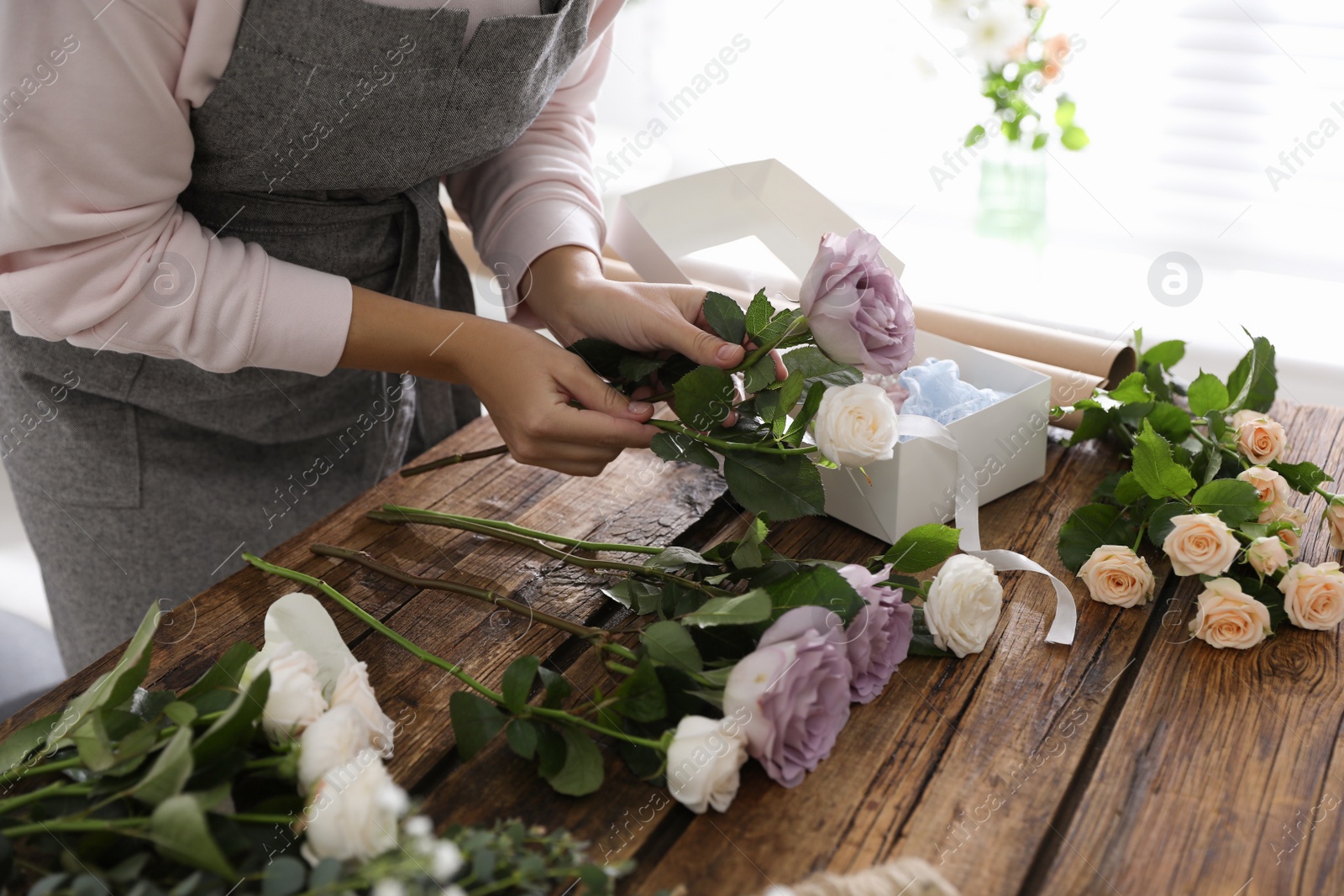 Photo of Florist making beautiful wedding bouquet at wooden table, closeup