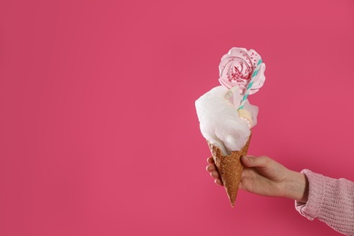 Woman holding tasty cotton candy dessert on pink background, closeup. Space for text