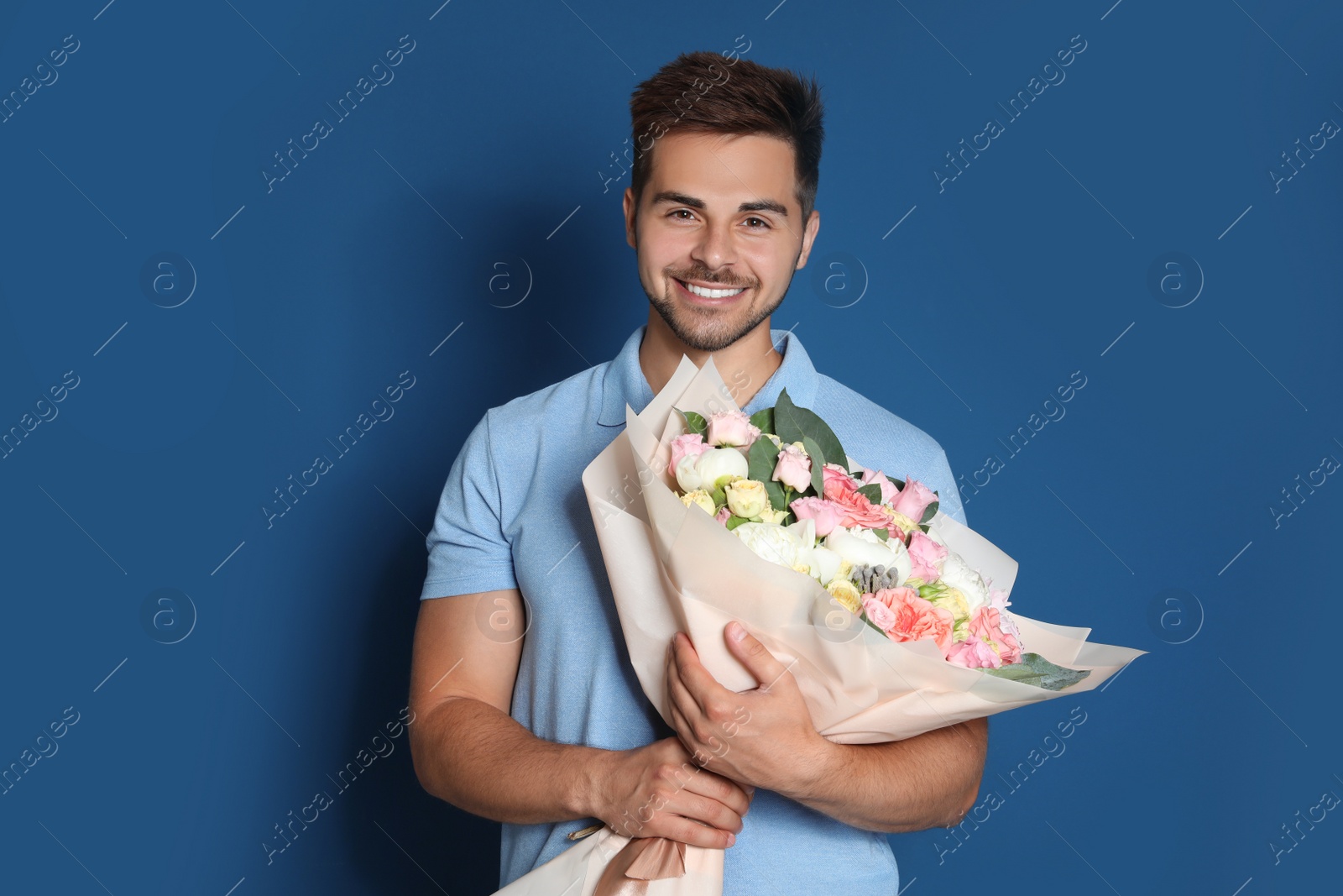 Photo of Young handsome man with beautiful flower bouquet on blue background