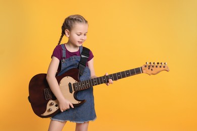 Cute girl with electric guitar on orange background