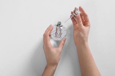 Woman with bottle of perfume on white background, top view