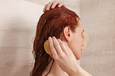 Photo of Young woman washing her hair with solid shampoo bar in shower