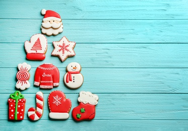 Photo of Christmas tree shape made of delicious gingerbread cookies on light blue wooden table, flat lay. Space for text