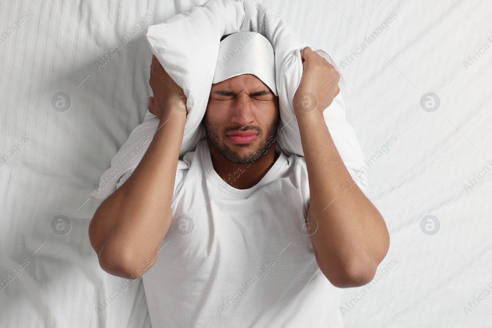 Photo of Man suffering from insomnia on bed, top view