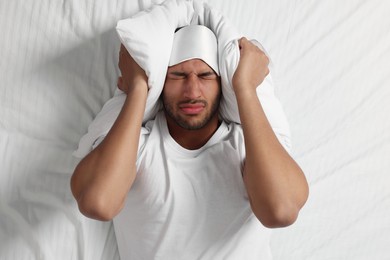 Photo of Man suffering from insomnia on bed, top view