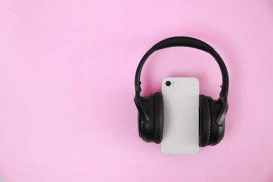 Photo of Modern wireless headphones and smartphone on pink background, top view. Space for text