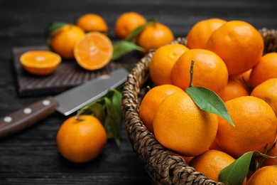 Photo of Fresh ripe tangerines in wicker basket on table