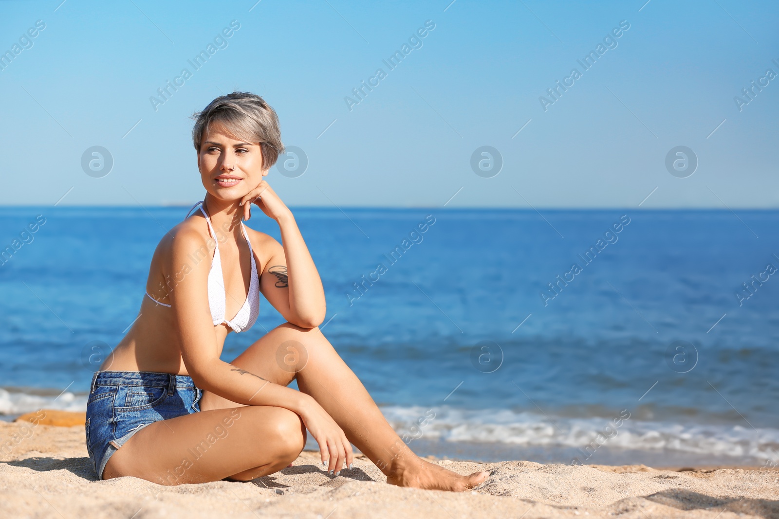 Photo of Young woman sitting on beach. Space for text