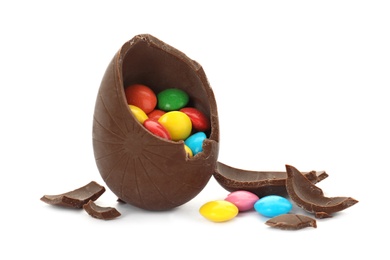 Photo of Broken chocolate egg with colorful candies on white background