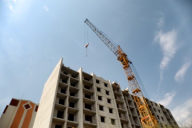 Photo of Blurred view of unfinished building and construction crane outdoors