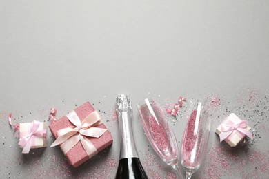 Photo of Flat lay composition with bottle of champagne for celebration on grey background. Space for text