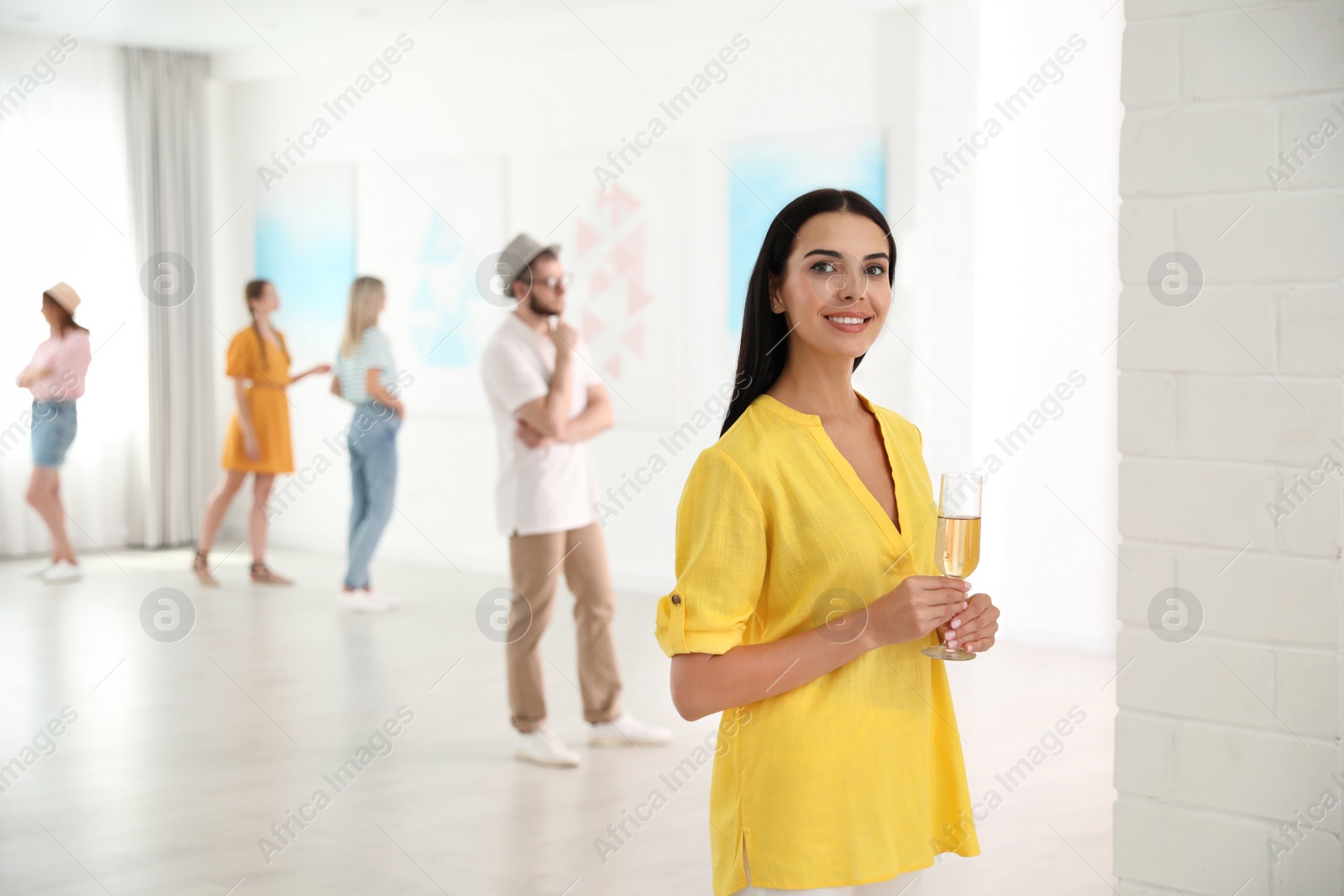 Photo of Young woman with glass of champagne at exhibition in art gallery