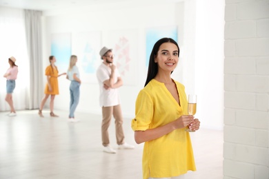 Young woman with glass of champagne at exhibition in art gallery