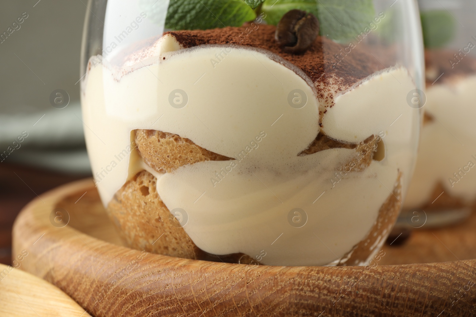 Photo of Delicious tiramisu in glass on table, closeup