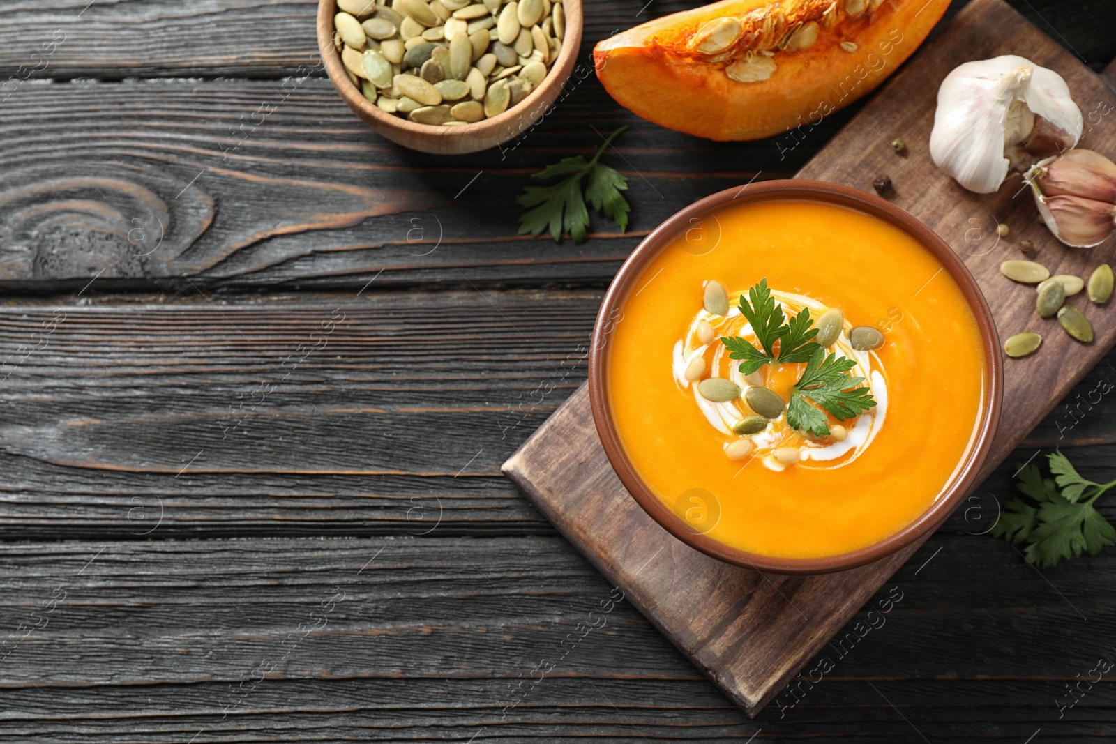 Photo of Delicious pumpkin soup in bowl on wooden table, flat lay. Space for text