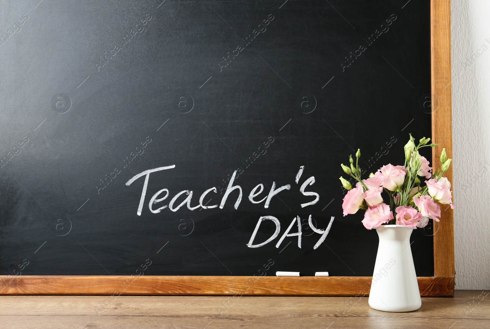 Photo of Blackboard with inscription TEACHER'S DAY and vase of flowers on wooden table, space for text