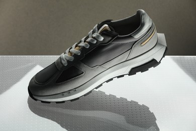 Photo of Stylish presentation of trendy sneaker against grey background